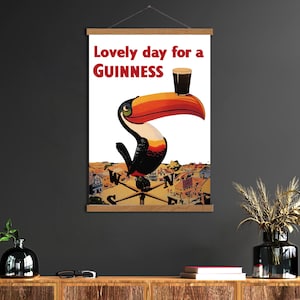 May include: A framed print featuring a toucan with a Guinness pint balanced on its beak. The text "Lovely day for a Guinness" is in red. The artwork has a vintage, illustrative style, with a cityscape background.