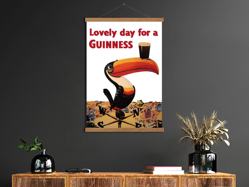 May include: A framed print featuring a toucan with a Guinness pint balanced on its beak. The text "Lovely day for a Guinness" is in red. The artwork has a vintage, illustrative style, with a cityscape background.