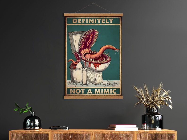 K&ouml;nnte beinhalten: Ein Poster mit dem Text "DEFINITELY NOT A MIMIC" zeigt eine Cartoon-Toilette mit einem monstr&ouml;sen Mund und einer Zunge. Das Kunstwerk ist vor einem teal-farbenen Hintergrund mit einem M&uuml;lleimer und einer Toilettenpapierrolle.