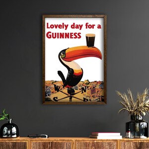 May include: Framed vintage Guinness advertisement featuring a toucan with a large orange and black beak, holding a pint of Guinness. The text reads "Lovely day for a Guinness" in red letters.