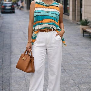 Könnte beinhalten: Ein ärmelloses Oberteil mit horizontalen Streifen in Türkis, Orange und Weiß wird mit einer weißen Hose und einem braunen Gürtel kombiniert. Eine braune Handtasche und Sonnenbrille vervollständigen das Outfit. Der Gesamtstil ist schick und modisch.