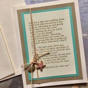 May include: A handmade greeting card with a beach theme. The card features a printed poem on a teal and brown background, adorned with a starfish and shell charm tied with twine. The card is on a white background.