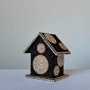 Handcrafted black glitter house with large round rhinestone embellishments and gold bead detailing, angled right view.
