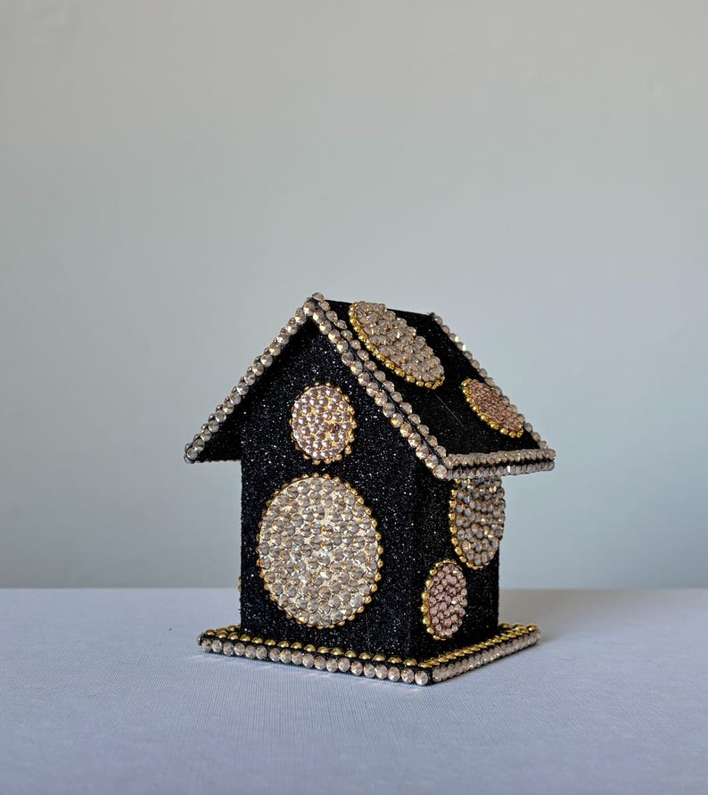 Handcrafted black glitter house with large round rhinestone embellishments and gold bead detailing, angled right view.