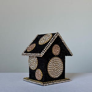 Black glitter miniature house decorated with gold rhinestone circles and crystal trim, angled left view on white background.