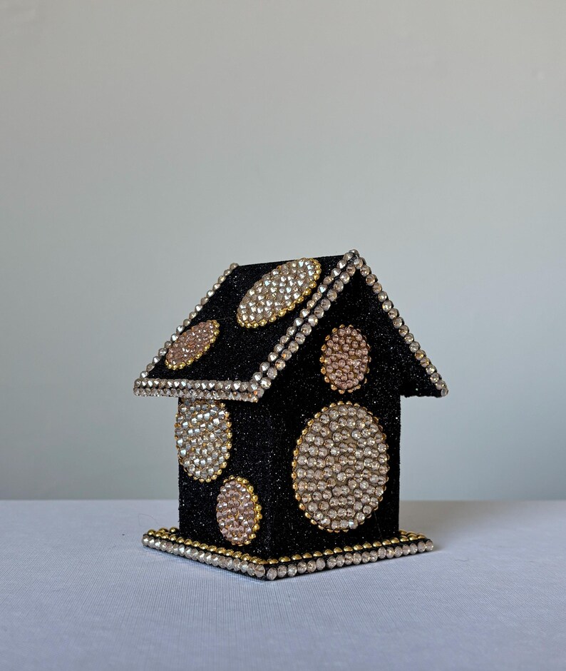 Black glitter miniature house decorated with gold rhinestone circles and crystal trim, angled left view on white background.