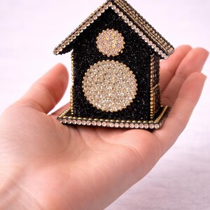Small black glitter crystal house held in palm of hand showing scale and detailed rhinestone embellishments.