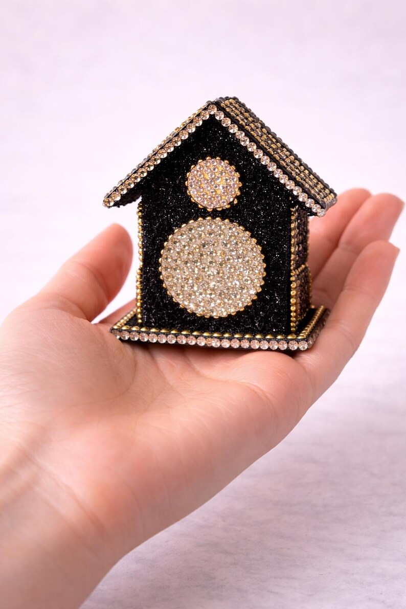 Small black glitter crystal house held in palm of hand showing scale and detailed rhinestone embellishments.