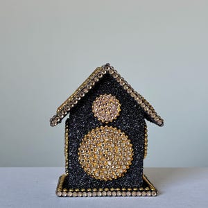 Back view of black glitter decorative mini house showing crystal-trimmed roof and gold beaded edges on clean white backdrop.