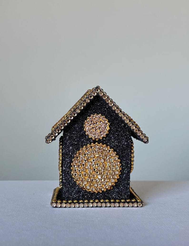 Back view of black glitter decorative mini house showing crystal-trimmed roof and gold beaded edges on clean white backdrop.