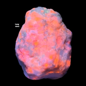May include: A glowing rock formation with a mix of pink, orange, and blue hues. The text "Long wave" is visible on the left side of the image. The rock has a rough, textured surface and is set against a black background.