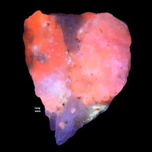 May include: A close-up of a mineral specimen with a vibrant color palette. The rock features a mix of pink, orange, and purple hues, with the text "Long wave" in white. The background is solid black, highlighting the mineral's unique colors and textures.