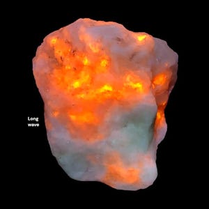 May include: A glowing, irregularly shaped rock with a mix of pale and vibrant orange hues. The text "Long wave" is visible on the left side of the image. The rock appears to be illuminated from within, creating a striking visual effect.