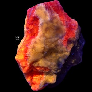 May include: A close-up of a rock formation with vibrant colors. The rock has a mix of orange, red, and yellow hues, with the text "Long wave" in the upper left corner. The background is black.