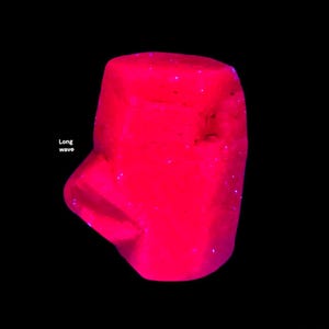 Könnte beinhalten: Ein leuchtend rosa Objekt unregelmäßiger Form vor schwarzem Hintergrund. Das Objekt hat eine abgerundete Oberseite und eine strukturierte Oberfläche. Die Worte "Long wave" stehen in weißem Text auf der linken Seite.