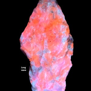 May include: A glowing, irregularly shaped rock formation with a vibrant color palette of pink, orange, and blue hues. The text "Long wave" is visible on the left side of the image. The rock's surface has a textured appearance against a black background.