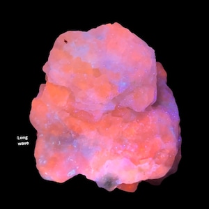 May include: A close-up of a mineral specimen with a rough, textured surface. The rock is primarily orange and pink, with hints of blue and purple. The words "Long wave" are in white text on the left side of the image.
