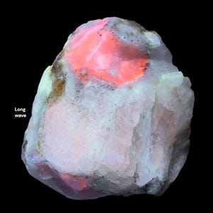 May include: A close-up of a mineral specimen with a glowing, vibrant orange center and white and gray outer layers. The text "Long wave" is visible in the image. The background is black.