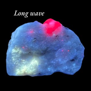 Könnte beinhalten: Ein unregelmäßig geformtes Mineral, das in Blau, Weiß und Rot leuchtet. Der Text "Long wave" steht in Weiß oben links.
