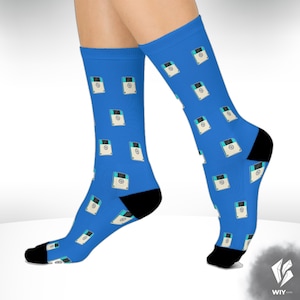 May include: Bright blue socks patterned with retro floppy disk designs. The socks have black heels and toes. The design features white, light blue, and black details on a bright blue background. A fun accessory.