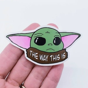 May include: A green and pink cartoon character with large eyes and the text "The Way This Is" on a brown banner.
