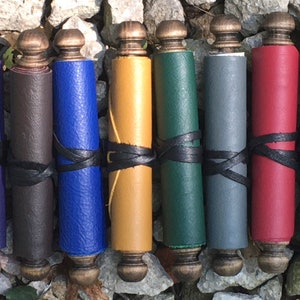May include: Eight leather-bound scrolls in various colors, including purple, brown, blue, yellow, green, gray, red, and teal. Each scroll is tied with a black leather strap and has a wooden knob at each end.