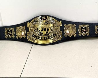 以下が含まれることがあります： 「WORLD WRESTLING ENTERTAINMENT」と「CHAMPION」の文字が入った、黒と金のチャンピオンベルト。 ベルトの中央には鷲と地球儀のデザイン、両サイドには小さなプレートが付いています。