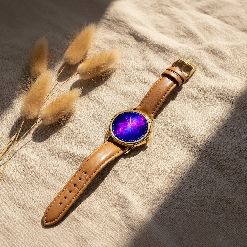May include: A gold-toned wristwatch with a brown leather band. The watch face displays a vibrant purple and blue galaxy design. The watch is set against a neutral background with dried flowers.