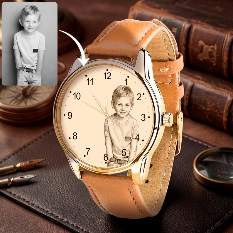 May include: A gold-toned wristwatch with a light brown leather band. The watch face features a portrait of a young boy, with black numerals marking the hours. The watch is set on a dark brown leather surface.