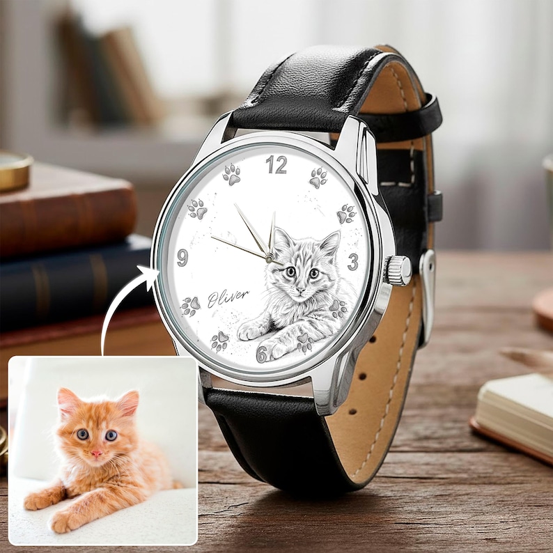 May include: A silver wristwatch with a black leather band. The watch face features a detailed sketch of a cat, paw prints, and the name "Oliver". The watch has silver hands and a silver bezel.