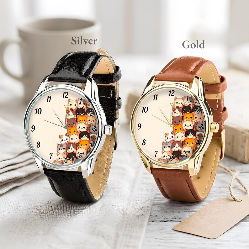 May include: Two wristwatches with cream-colored faces and black leather bands. One watch has a silver case, the other a gold case. The watch faces feature a pattern of stacked cartoon cats. The word "Silver" is above the silver watch, and "Gold" is above the gold watch.