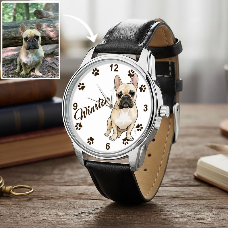 May include: A silver wristwatch with a black leather band. The watch face features a tan and white French Bulldog illustration, paw prints, and the name "Winston". A smaller image of the dog is in the upper left corner.