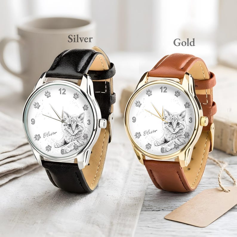 May include: Two wristwatches with cat-themed faces. One watch has a silver case and a black leather band, the other has a gold case and a brown leather band. The watch faces feature a cat illustration, paw prints, and the name "Oliver".