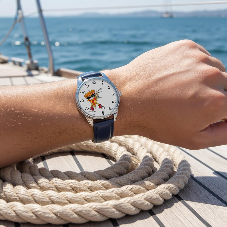 May include: A wristwatch with a silver-tone case and a dark blue leather strap. The white watch face features a cartoon illustration of a slice of pizza wearing sunglasses and red sneakers, performing a dabbing pose, with black numerals.