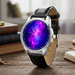 May include: A silver wristwatch with a black leather band. The watch face displays a vibrant nebula design in shades of blue, purple, and pink. The watch is set on a wooden surface, with books in the background.