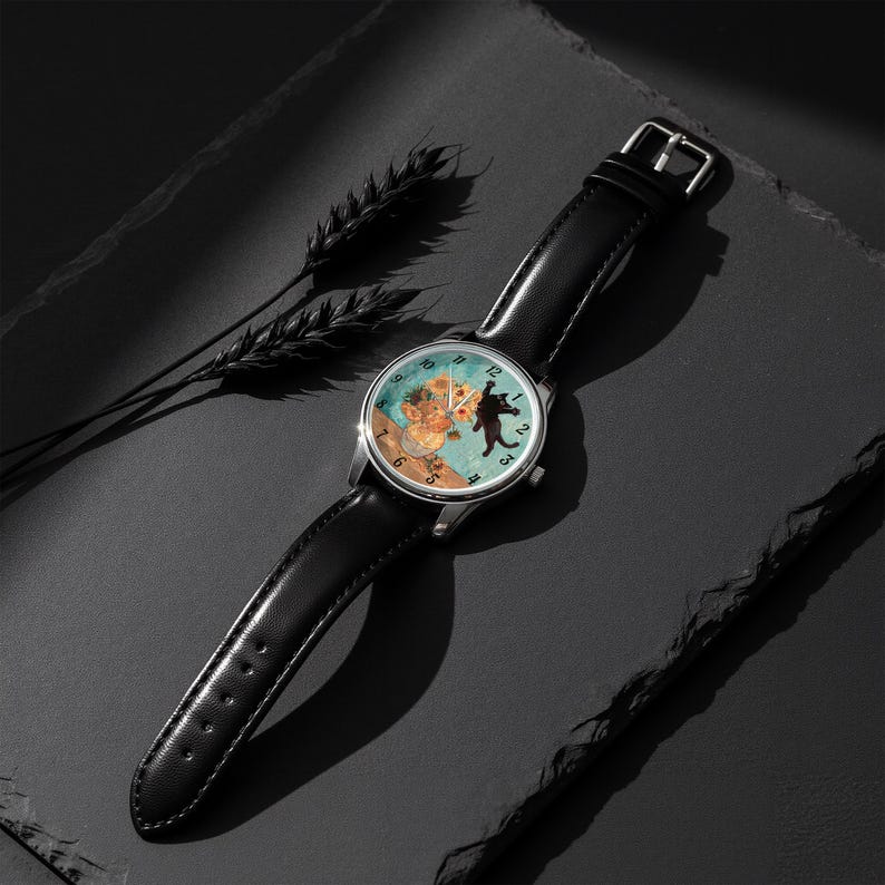 Puede incluir: Un reloj de pulsera con una correa de cuero negro y una caja plateada. La esfera del reloj presenta una ilustraci&oacute;n caprichosa de un oso y un gato. El fondo de la esfera es de color azul claro.