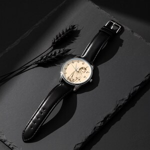 May include: A silver wristwatch with a black leather band. The watch face features a sepia-toned image of a person. The watch is set against a dark background with a sprig of wheat.