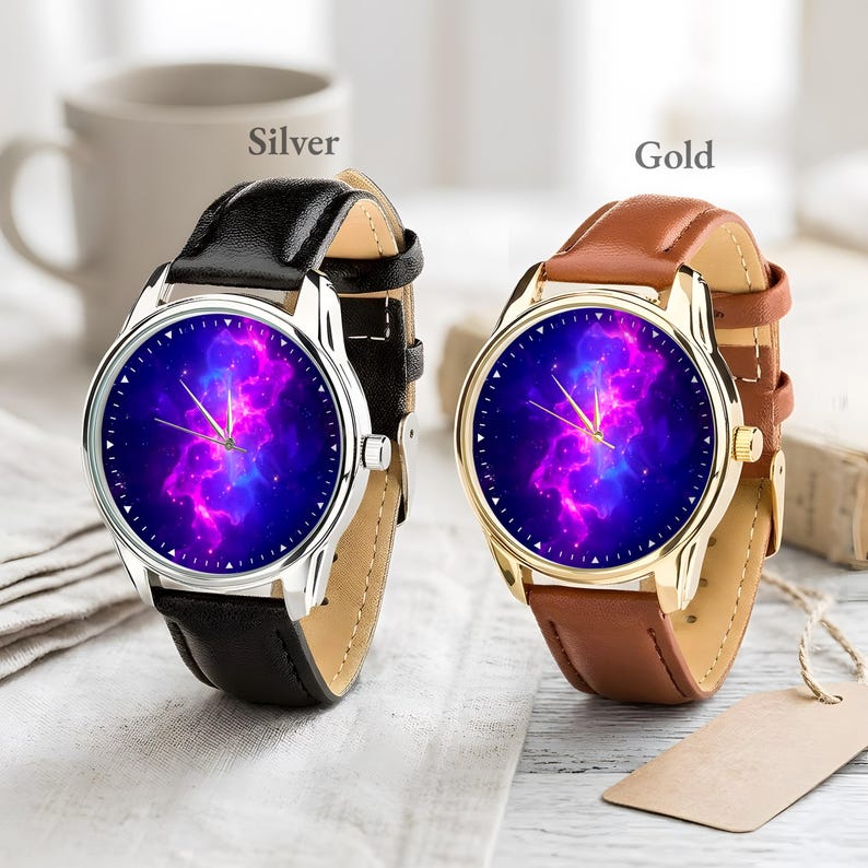 May include: Two watches with leather bands. One has a silver case and a black band, the other has a gold case and a brown band. Both watches have a blue and purple galaxy design on the watch face.