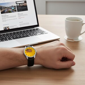 May include: A wristwatch with a silver-tone case and a black leather strap. The watch face is bright yellow and features a graphic illustration of three cartoon potato characters wearing sunglasses and hats, with black numerals marking the hours.