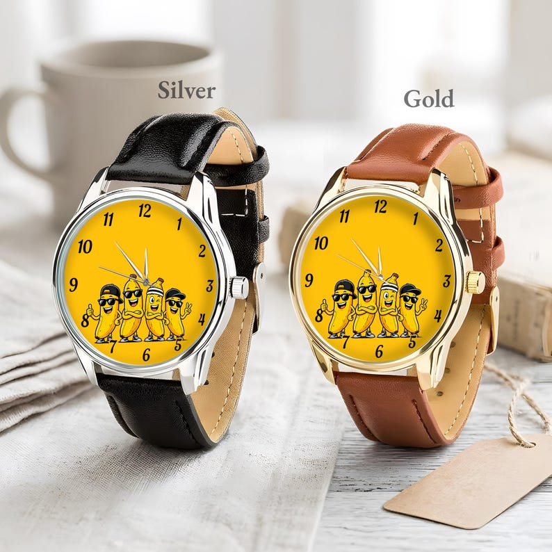 Puede incluir: Dos relojes de pulsera con esferas amarillas que muestran un gr&aacute;fico de cuatro pl&aacute;tanos de dibujos animados con gafas de sol y sombreros. Uno tiene caja plateada con correa de cuero negra y el otro caja dorada con correa de cuero marr&oacute;n.