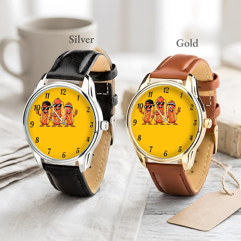 May include: Two wristwatches with yellow faces featuring a graphic of three cartoon hot dogs. One watch has a silver-tone case and a black leather strap, while the other has a gold-tone case and a brown leather strap. Both have black numerals.