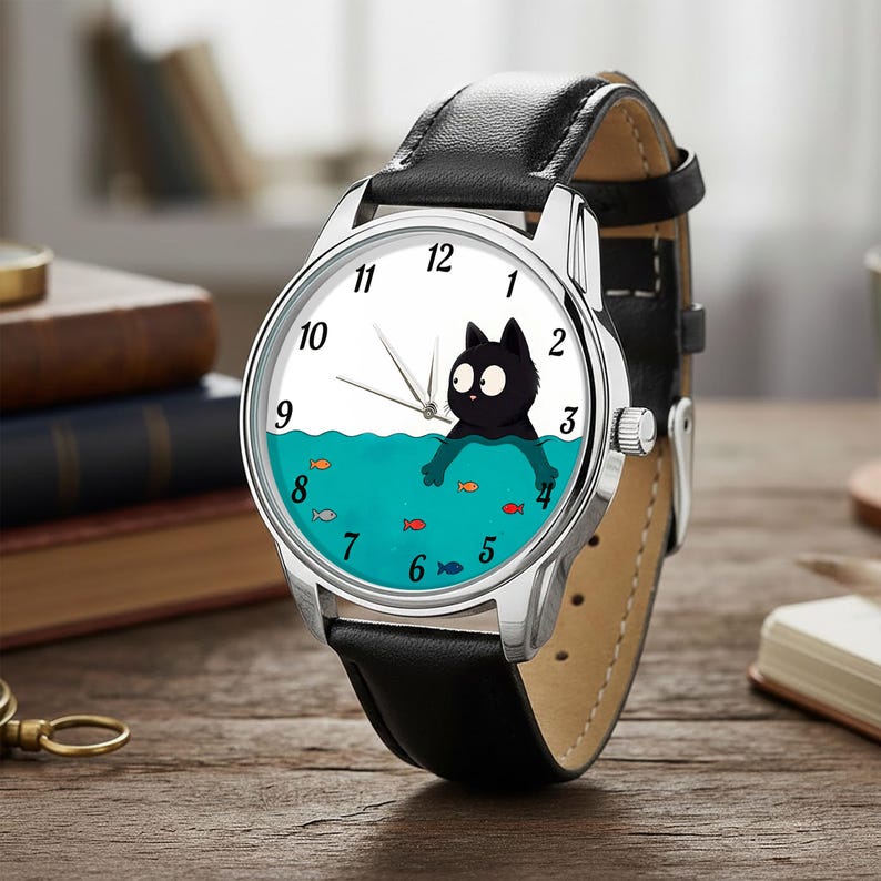 Pu&ograve; includere: Orologio da polso color argento con cinturino in pelle nera. Il quadrante dell'orologio presenta un gatto nero nell'acqua con pesci e l'ora &egrave; indicata da lancette argentate e numeri neri.