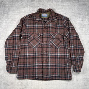 May include: A brown, red, black, and blue plaid button-down shirt. The long-sleeved shirt has two chest pockets and a collar. The shirt is made of a thick, warm material, perfect for cooler weather. The shirt is laid flat on a gray surface.