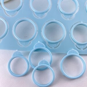 Pu&ograve; includere: Una dima in plastica azzurra per misurare gli anelli con molteplici fori circolari di varie dimensioni. Ogni foro &egrave; contrassegnato da numeri che indicano la misura, inclusi 8, 10,5 e 11,5, con diversi pezzi singoli di misurazione staccati.