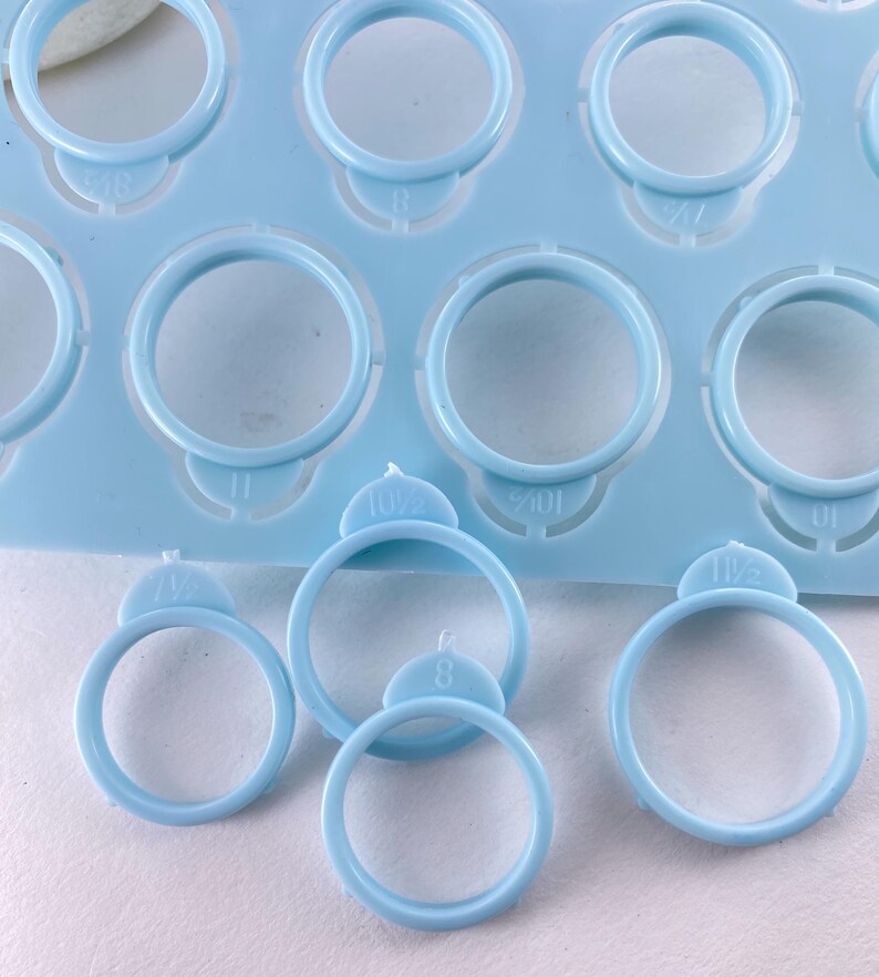 Pu&ograve; includere: Una dima in plastica azzurra per misurare gli anelli con molteplici fori circolari di varie dimensioni. Ogni foro &egrave; contrassegnato da numeri che indicano la misura, inclusi 8, 10,5 e 11,5, con diversi pezzi singoli di misurazione staccati.