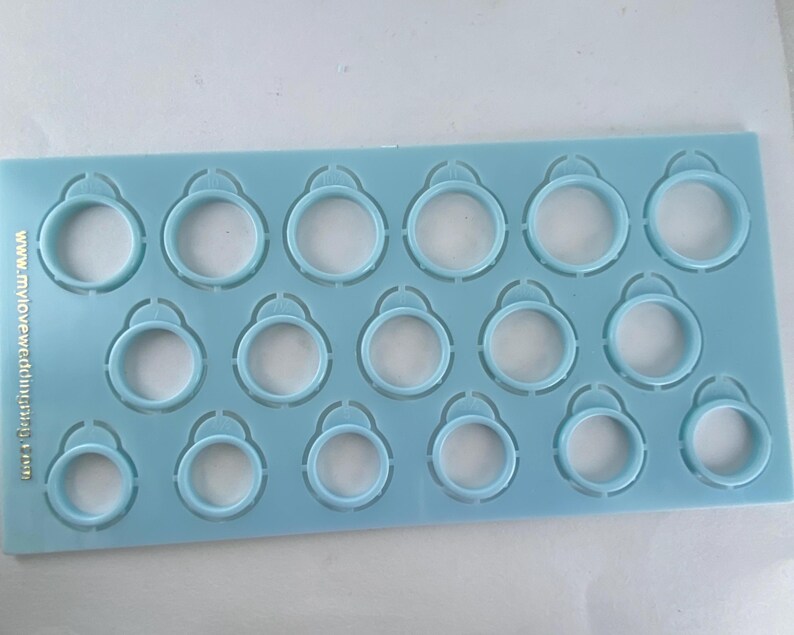 Pu&ograve; includere: Una dima rettangolare in plastica azzurra per misurare gli anelli, dotata di diciotto fori circolari di varie dimensioni. Il testo www.myloveweddingring.com &egrave; stampato verticalmente in oro sul lato sinistro dello strumento.
