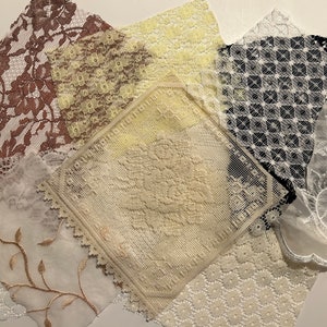 May include: Assortment of lace fabric scraps in various colors and patterns, including white, black, brown, and yellow. The lace is delicate and intricate, with floral and geometric designs.