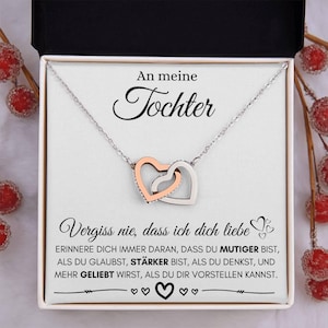 Peut inclure: Un collier argenté avec deux pendentifs en forme de cœur entrelacés, l'un en or rose et l'autre en argent, présenté dans un coffret cadeau. La boîte contient du texte en allemand : "An meine Tochter" et un message d'amour.