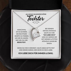 May include: A silver-toned heart pendant necklace with a clear crystal center, presented in a black gift box. The card inside reads "AN MEINE WUNDERSCHÖNE Tochter" and includes a loving message. A thoughtful gift.