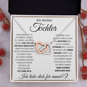Peut inclure: Un collier argenté avec deux pendentifs en forme de cœur entrelacés, l'un en or rose et l'autre en argent, présenté dans un coffret cadeau. La boîte contient un message imprimé en allemand.